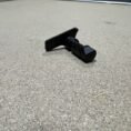 Sig Sauer P320 OEM stock takedown lever on textured surface for secure handling.