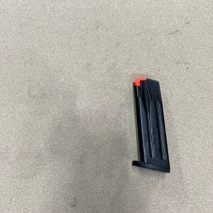 Black Sig Sauer P320 15-round magazine with red follower on a light surface.