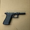 Glock 17 Gen 3 lower frame, factory OEM parts on cardboard surface, showcasing firearm features.