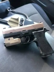 Tactical handgun with light in vehicle seat, ready with holster for personal defense.