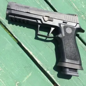 Modern black handgun on rustic wooden surface, showcasing sleek design and tactical features.