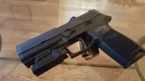 Matte black pistol with tactical light accessory, ideal for defense and law enforcement.