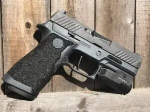 Modern semi-automatic pistol on weathered wood backdrop, showcasing sleek design and tactical features.