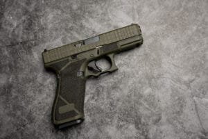 Olive green semi-automatic firearm closeup, showcasing tactical design and textured grip.
