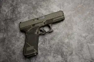 Olive green semi-automatic firearm closeup, showcasing tactical design and textured grip.