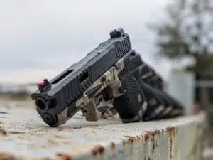 Close-up of a sleek handgun on a weathered metal surface, highlighting its design and detail.