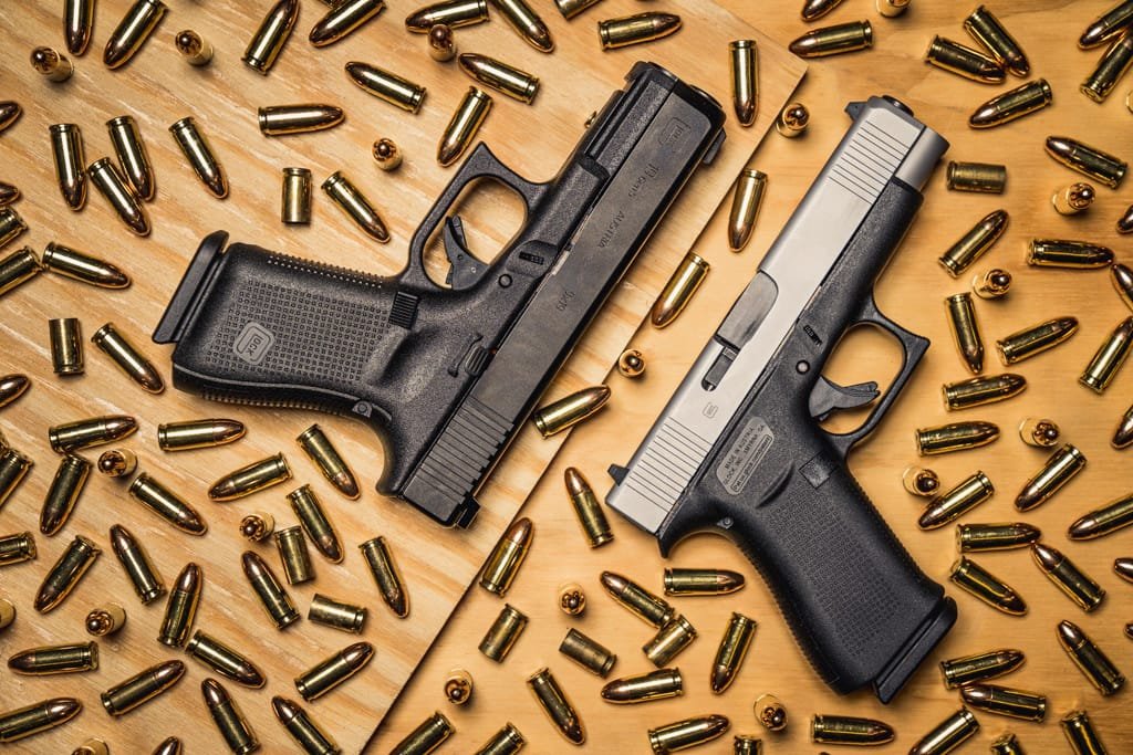 Glock 48 handguns on a wooden table with bullet casings, showcasing sleek design and functionality.
