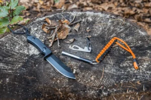 Outdoor survival knife, multi-tool, and orange paracord for camping and hiking adventures.